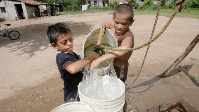 Zwei Jungen ziehen einen Eimer aus einem Brunnen in Pespire, Honduras 